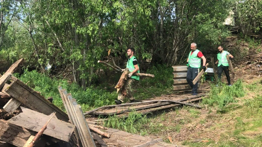 Рабочие пока вручную собирают хлам на берегу Полуя. Фото: Екатерина Золотарёва / ИА «Север-Пресс»