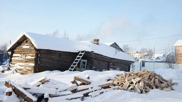 Здесь живут люди. Покосившаяся избушка, рядом гора наколотых дров, из трубы валит дым